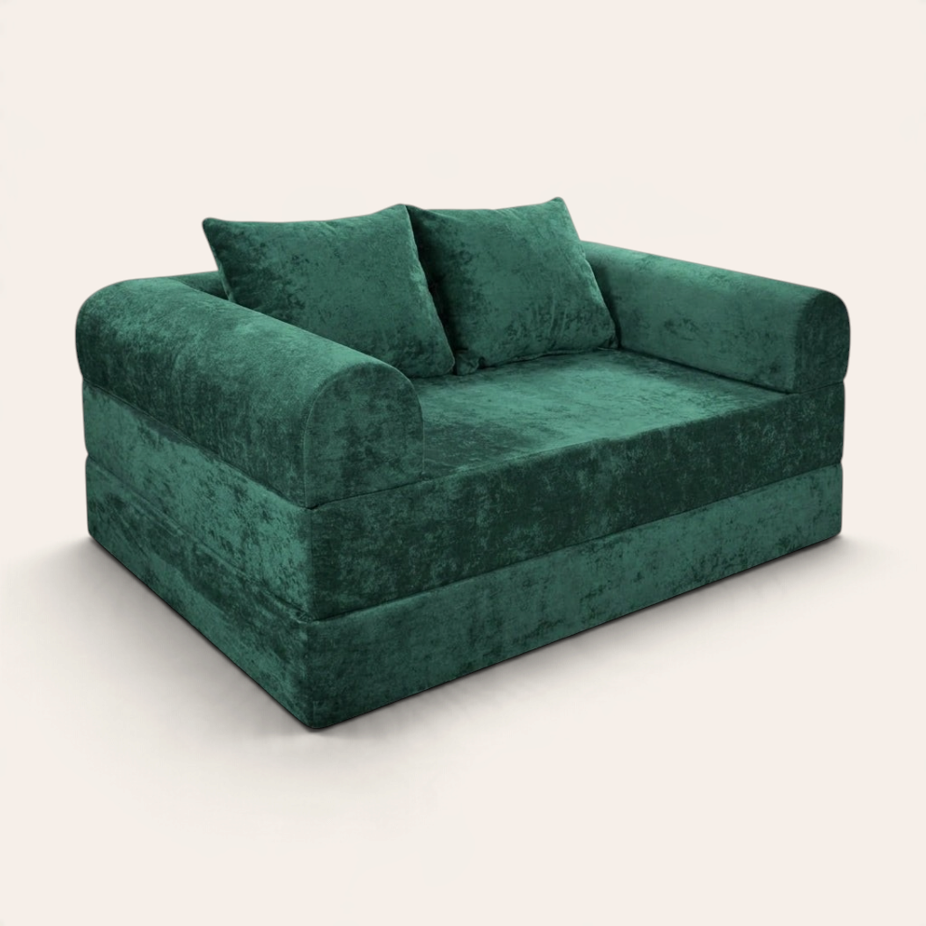 Sofá cama modular Naap Concept en color verde esmeralda con acabado de terciopelo suave y dos cojines decorativos.