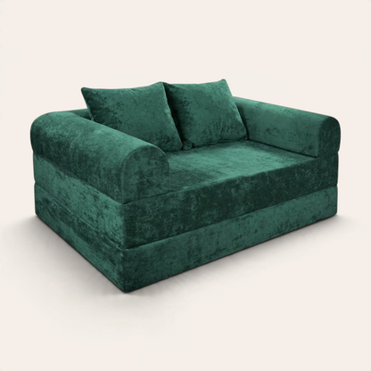 Sofá cama modular Naap Concept en color verde esmeralda con acabado de terciopelo suave y dos cojines decorativos.